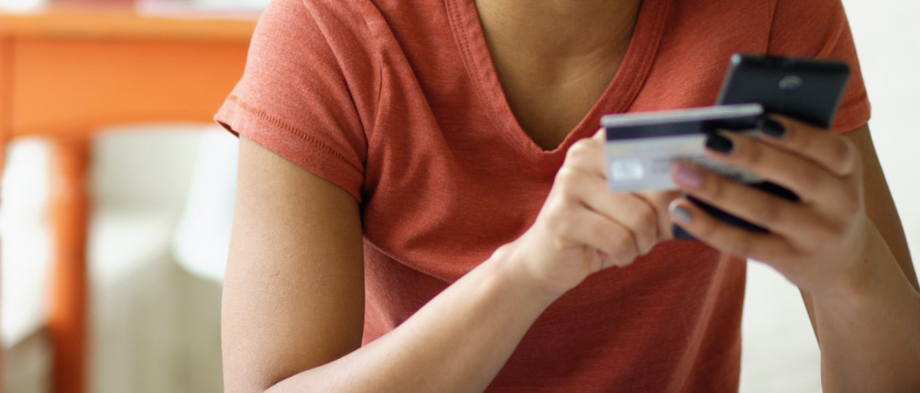 A woman using a debit/credit card while on a mobile device