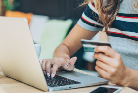 A woman at laptop holding debit/credit card