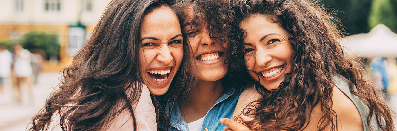 Three young friends hugging with big smiles