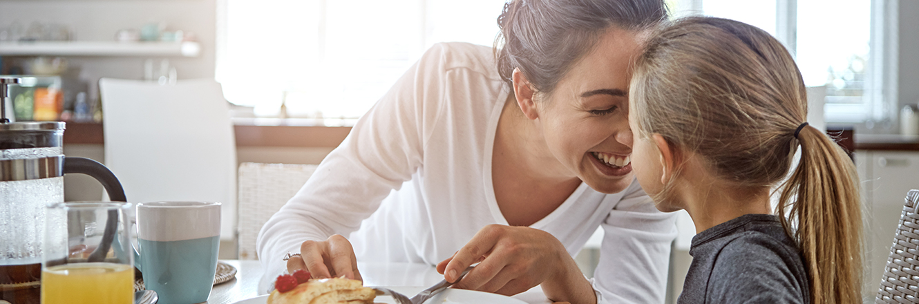 mother and young daughter having breakfast together