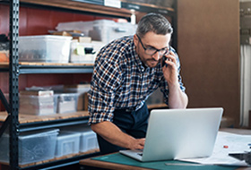 business man on phone looking at laptop