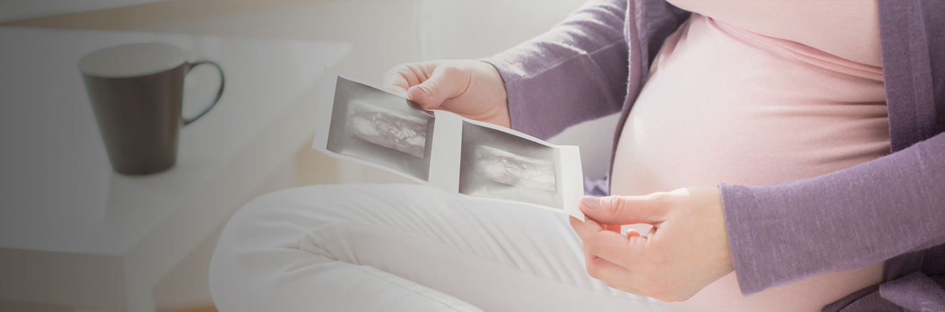 pregnant woman looking at ultrasound photo of baby