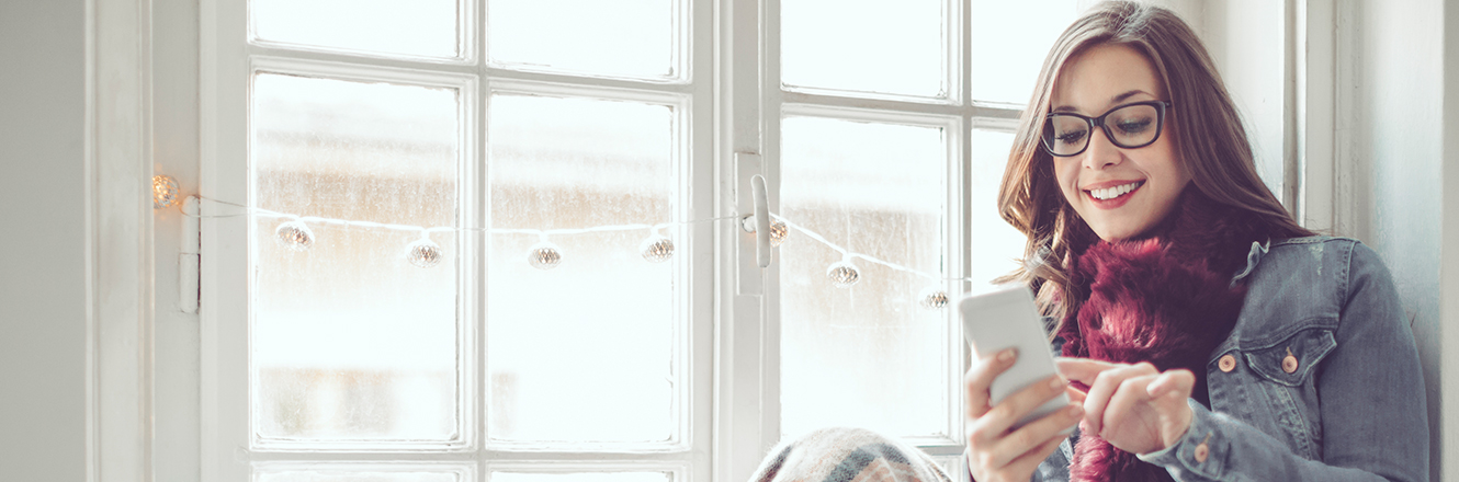 young woman looking at cell phone wearing fall sweater and scarf