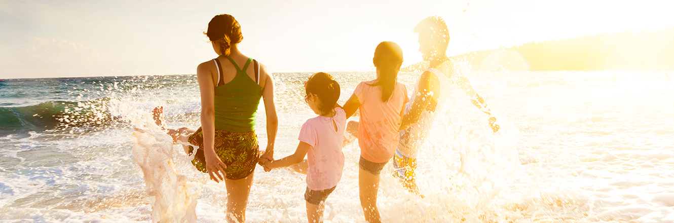 family holding hands in water at beach