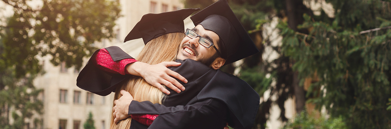 two high school graduates hugging after graduation