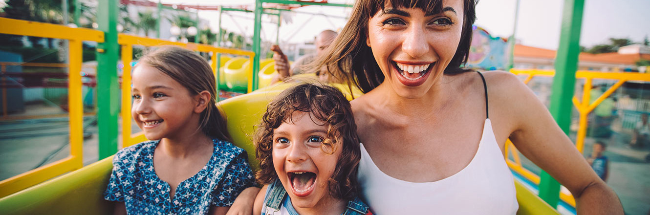Happy mom and two kids riding a fun roller coaster