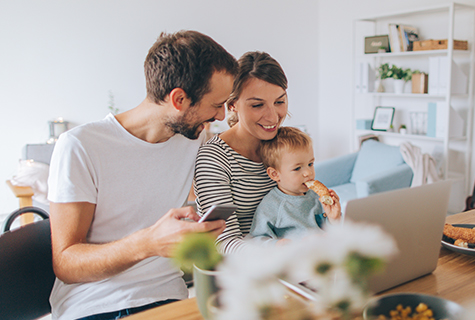 parents and child looking at computer in kitchen