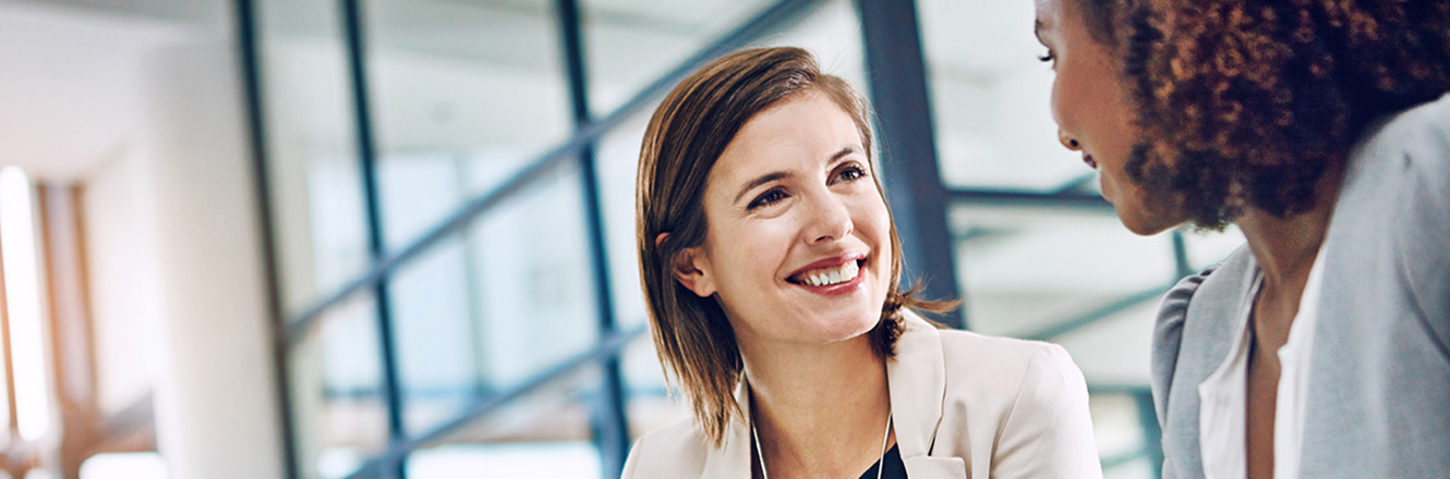 Two happy women in an office talking