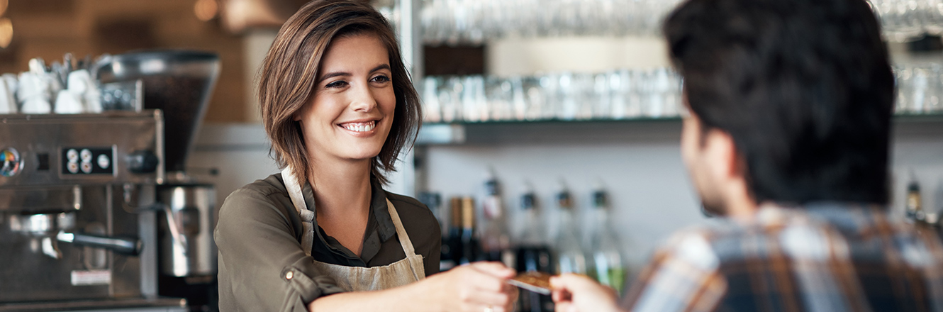man handing debit or credit card to barista at coffee shop