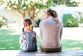 mother and young daughter sitting in backyard