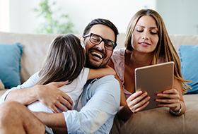 parents and child on couch with tablet