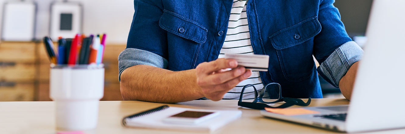 holding credit or debit card while typing on computer