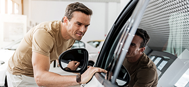 man looking at new car inside dealership