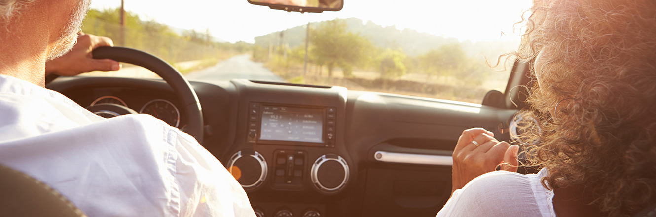 Mature couple riding through wine country in a new convertible car