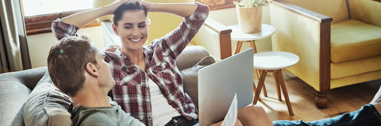 couple relaxing at home, looking at finances on laptop 