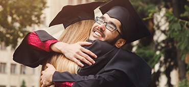 two high school graduates hugging after graduation