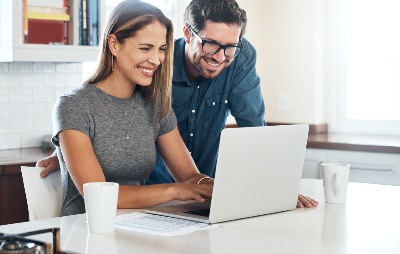 A happy couple looking at their laptop in their kitchen