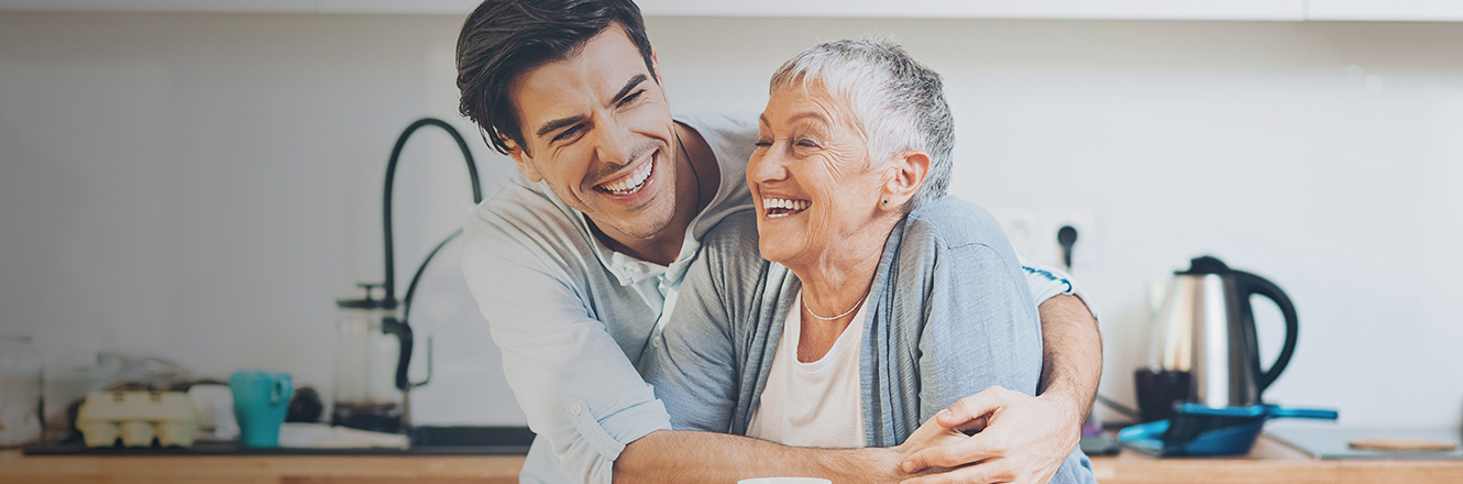 man hugging mother in kitchen