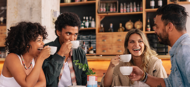 four friends talking and drinking coffee together