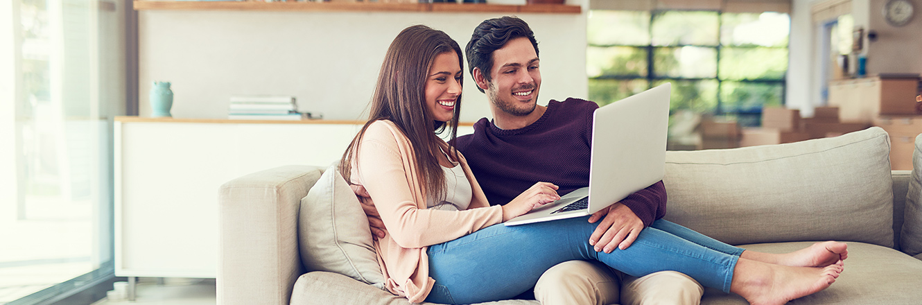 couple sitting on couch with laptop