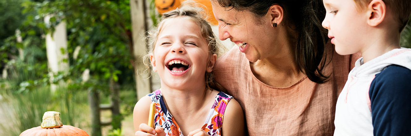 mom and two young kids laughing outside