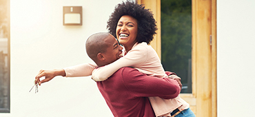 Couple hugging and holding house keys outside