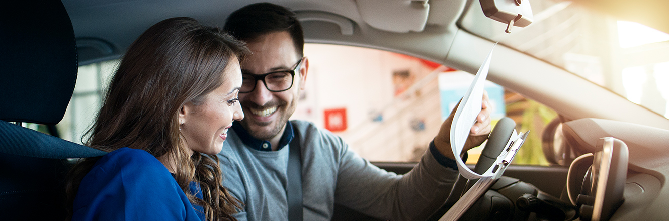 Man and woman sitting in car looking over paperwork