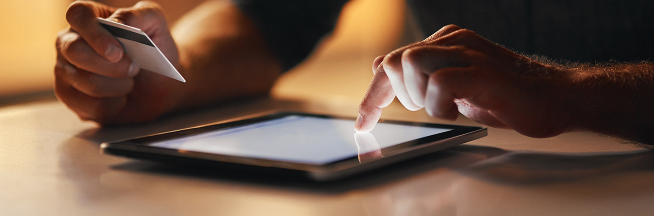 man holding credit card while using tablet