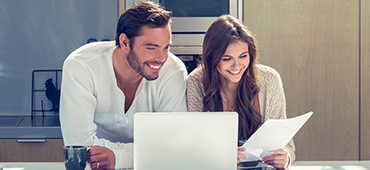 Couple looking at computer and paper in kitchen