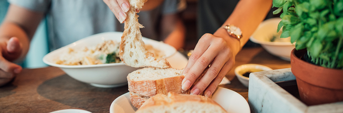 Woman tearing piece of bread at restaurant