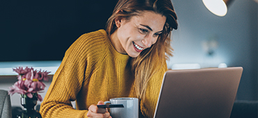 young woman using laptop with coffee cup and credit card