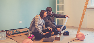 couple sitting on floor looking at renovation plans