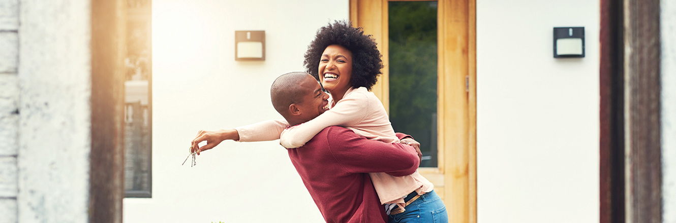 Couple hugging and holding house keys outside