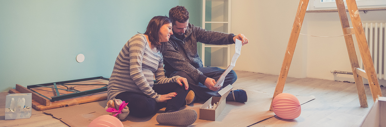 couple sitting on floor looking at renovation plans