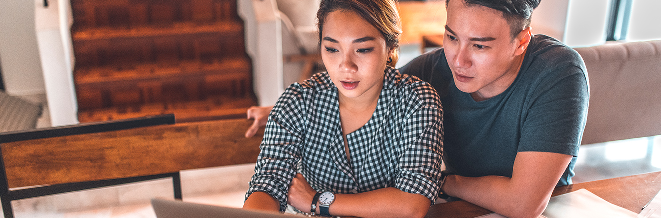 couple sitting at kitchen table looking at computer