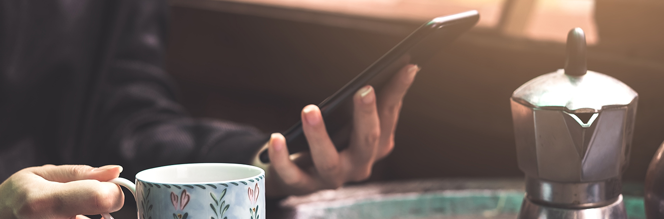 checking info on phone while sipping coffee