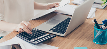 woman typing on calculator and computer