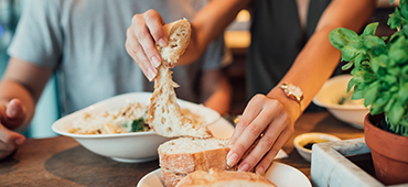 Woman tearing piece of bread at restaurant