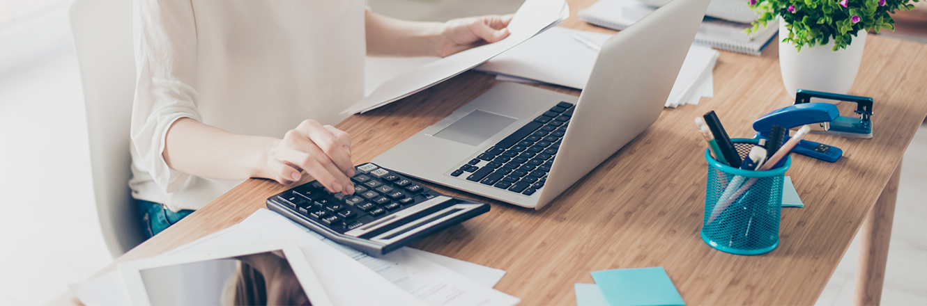 woman typing on calculator and computer