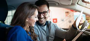 Man and woman sitting in car looking over paperwork