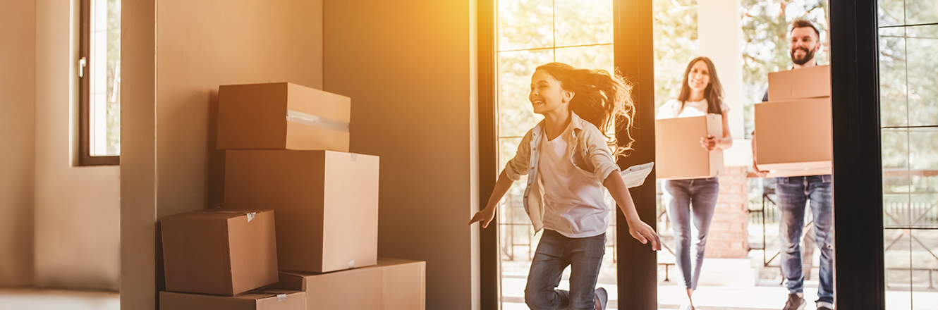 young girl running in to new home while parents are carrying boxes