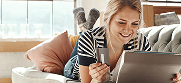 Woman sitting on couch with laptop and credit card