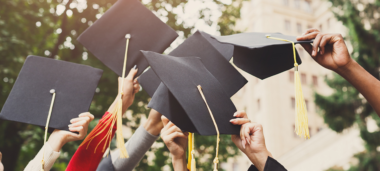 graduates holding up caps
