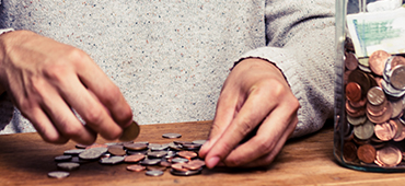 counting coins next to jar