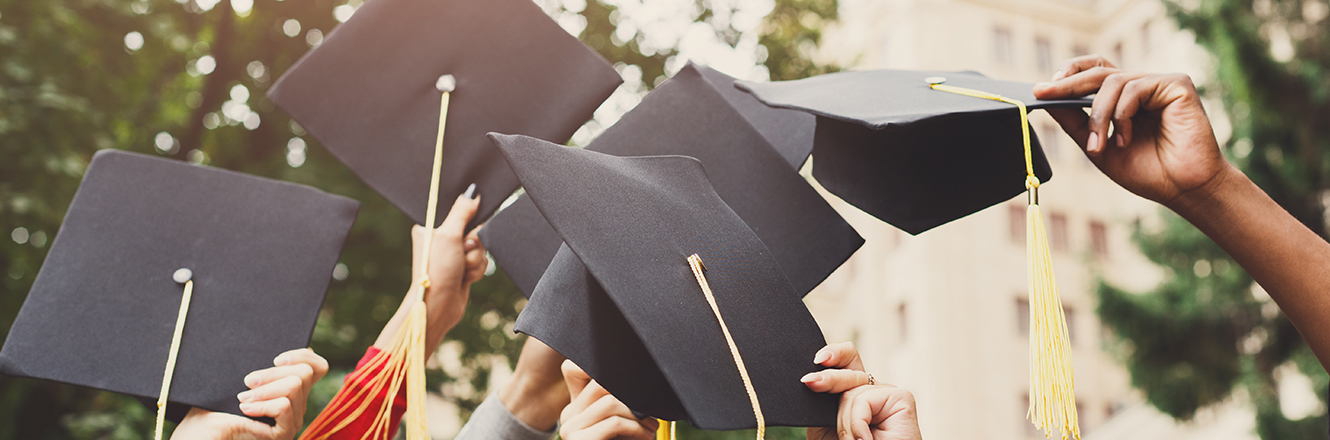 graduates holding up caps