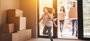 young girl running in to new home while parents are carrying boxes