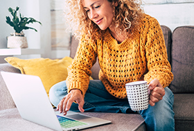 woman using laptop on couch with coffee